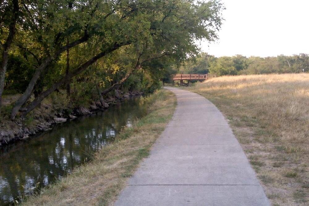 A creek lined with trees running through a greenbelt