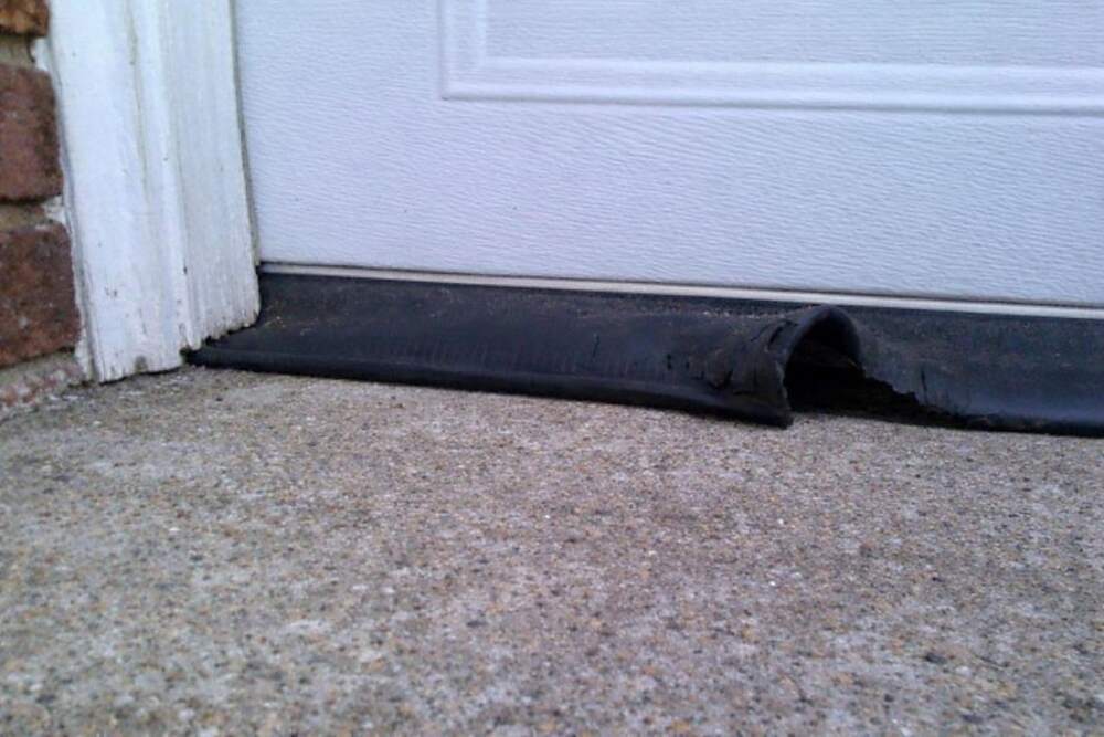 The bottom edge of a residential garage door where the weather seal meets the slab
