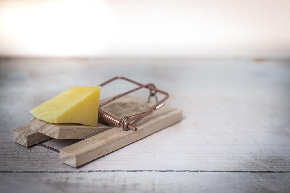 A wooden snap trap set on a wooden surface